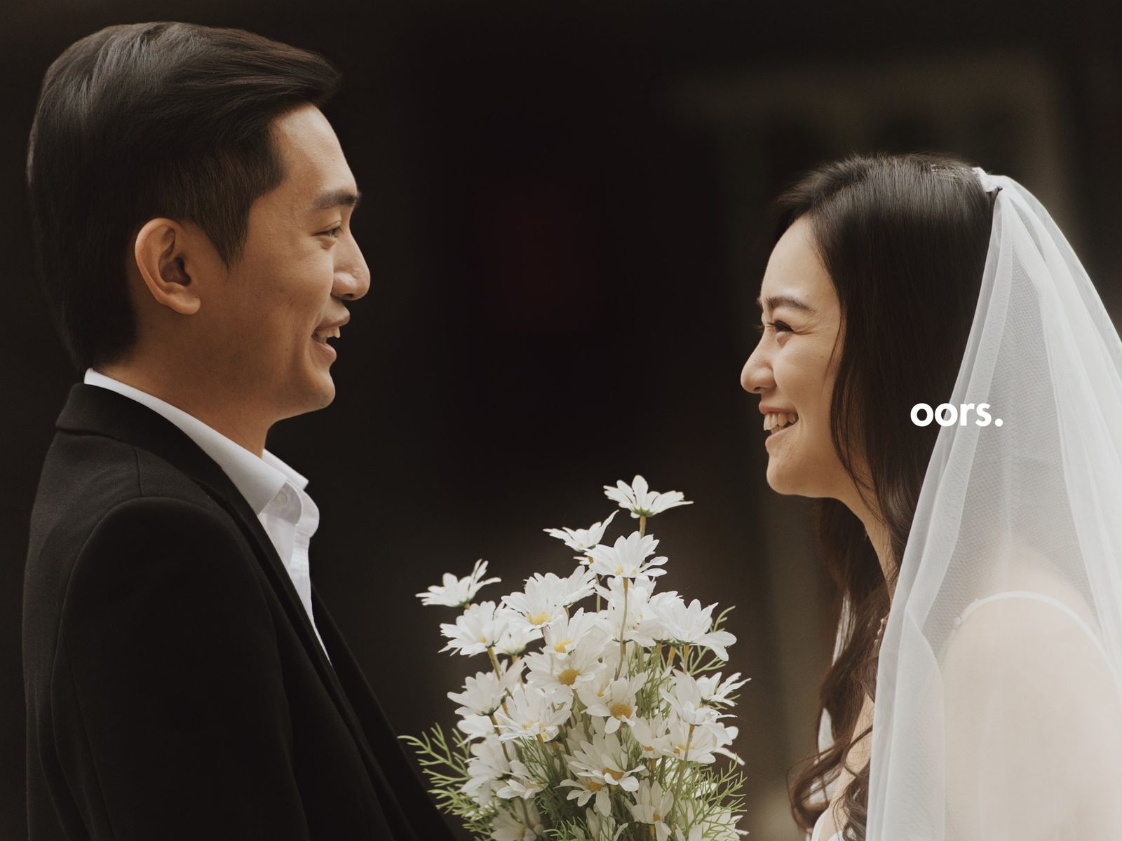 Close-up of the couple smiling at each other, daisies between them