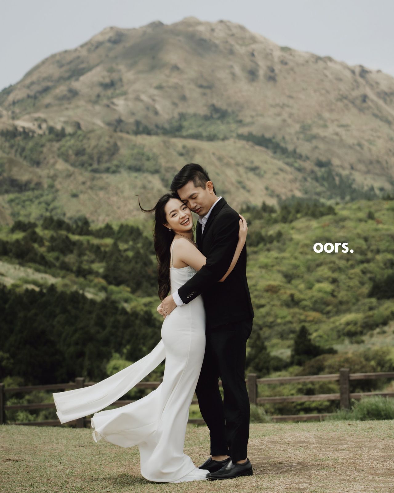 The couple embracing in front of a mountain