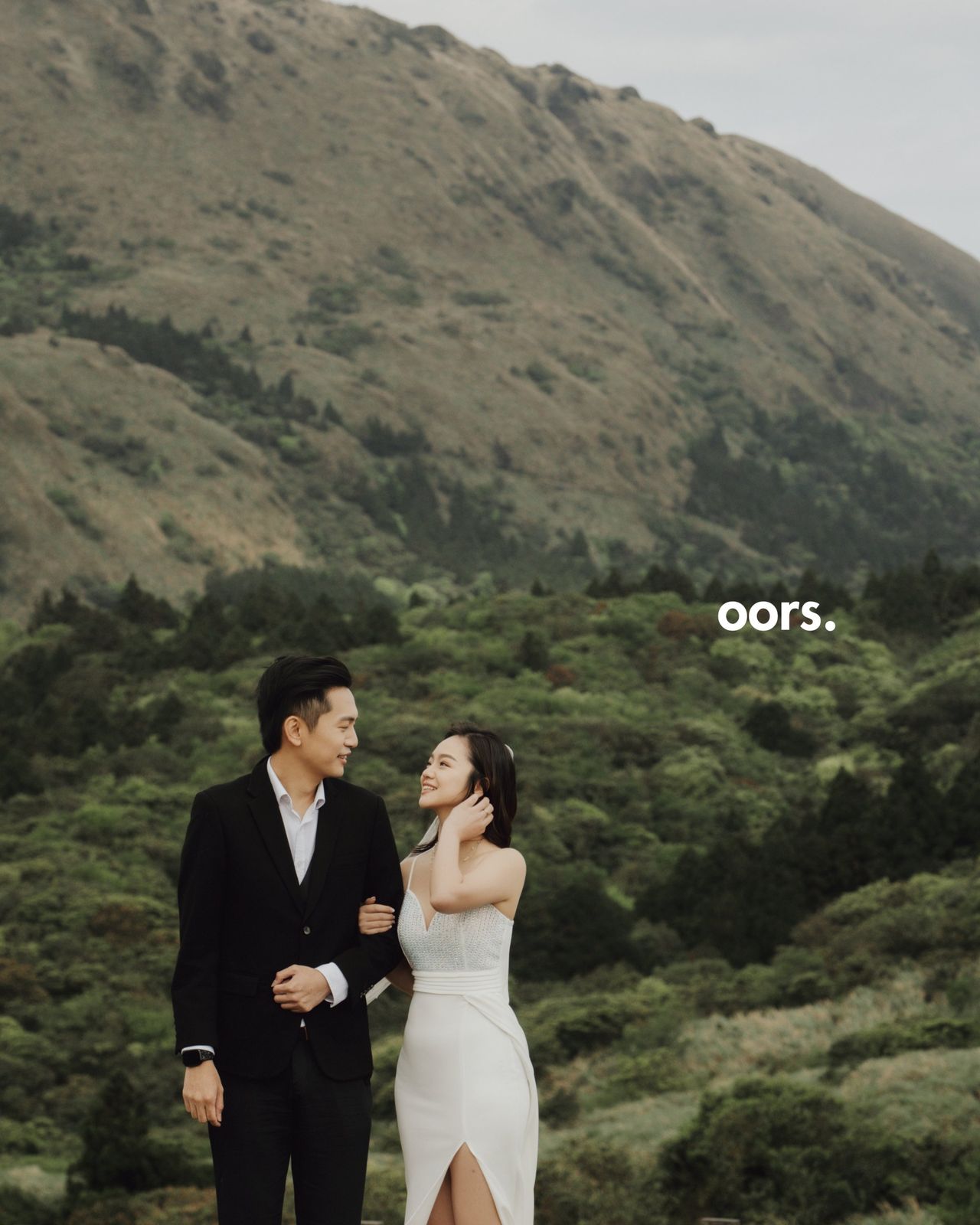 The couple arm in arm among the hills