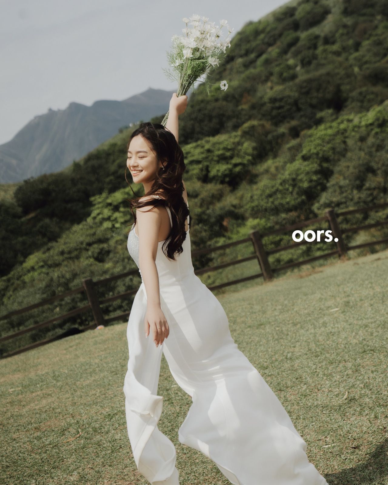 The bride running through the grass with daisies held high