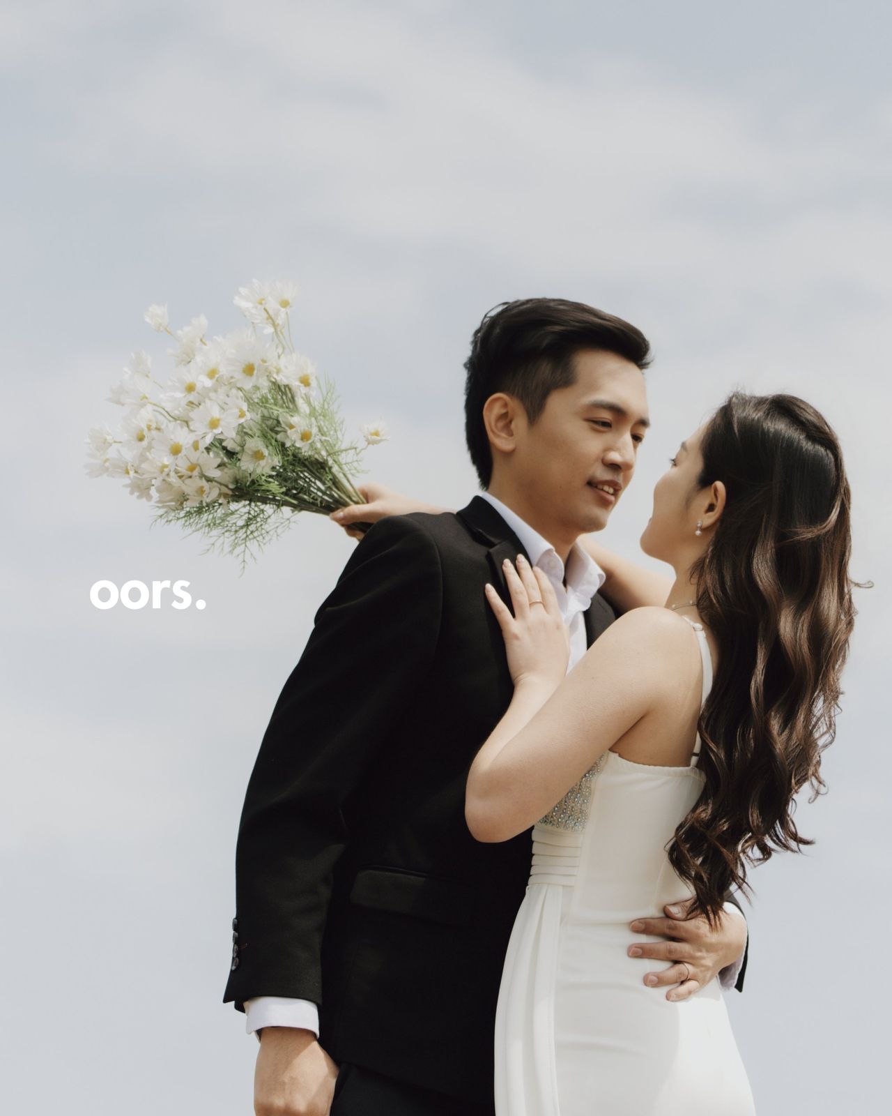 The couple against a soft cloudy sky