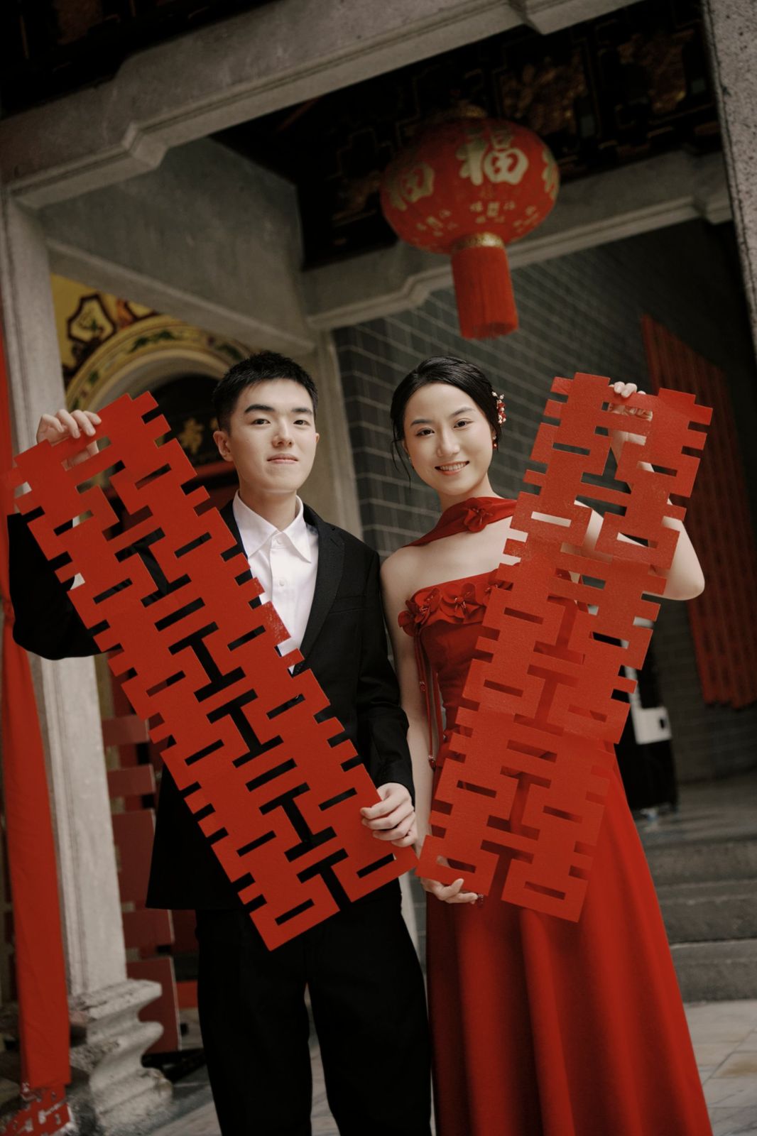 The couple holding red double-happiness papercuts
