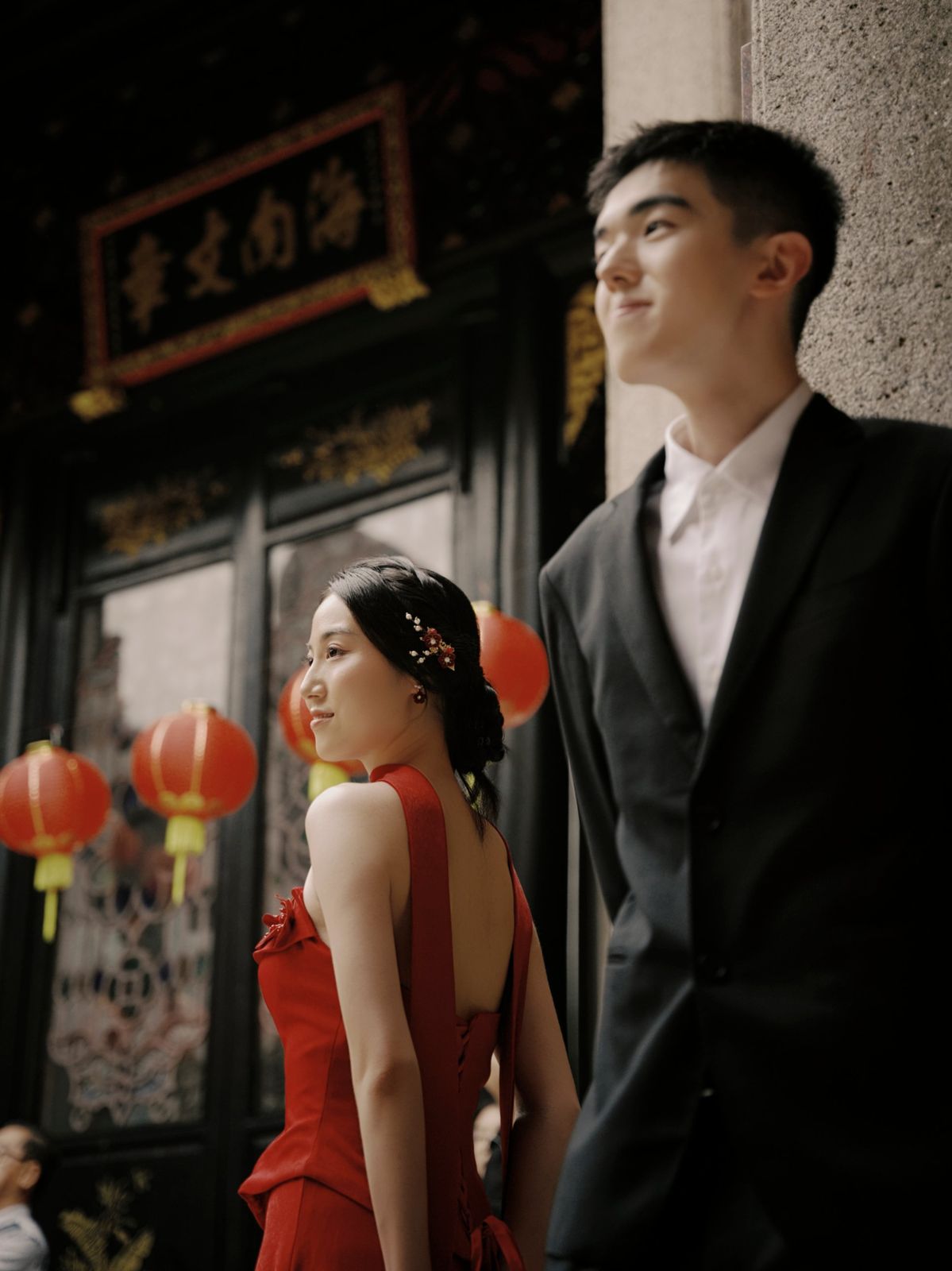 The couple glancing away beside the lanterns