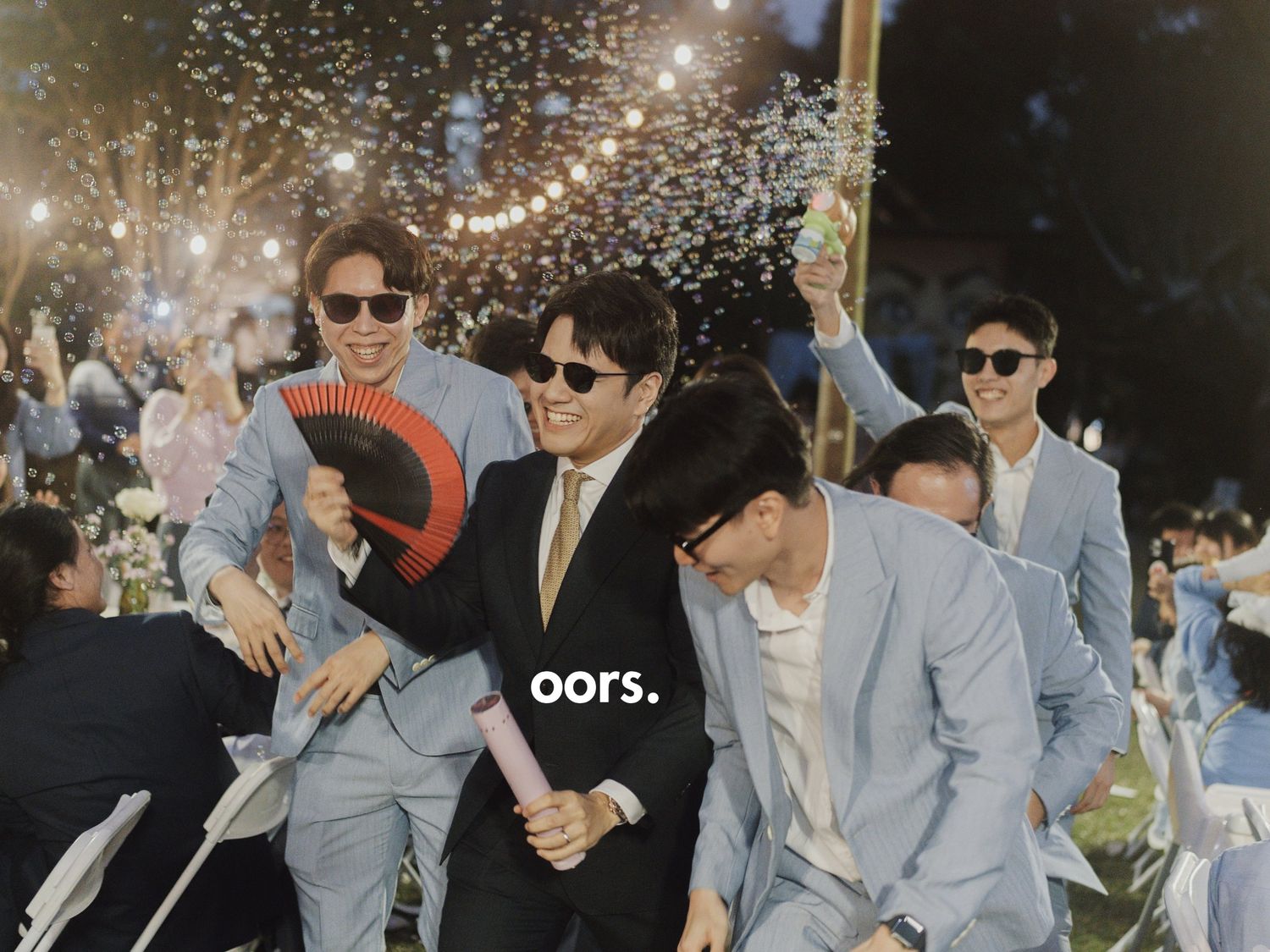 Groomsmen in sunglasses with bubbles and a red fan