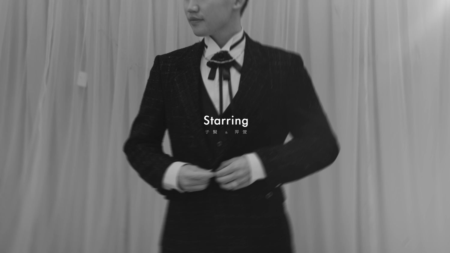 Black-and-white portrait of the groom adjusting his bow tie