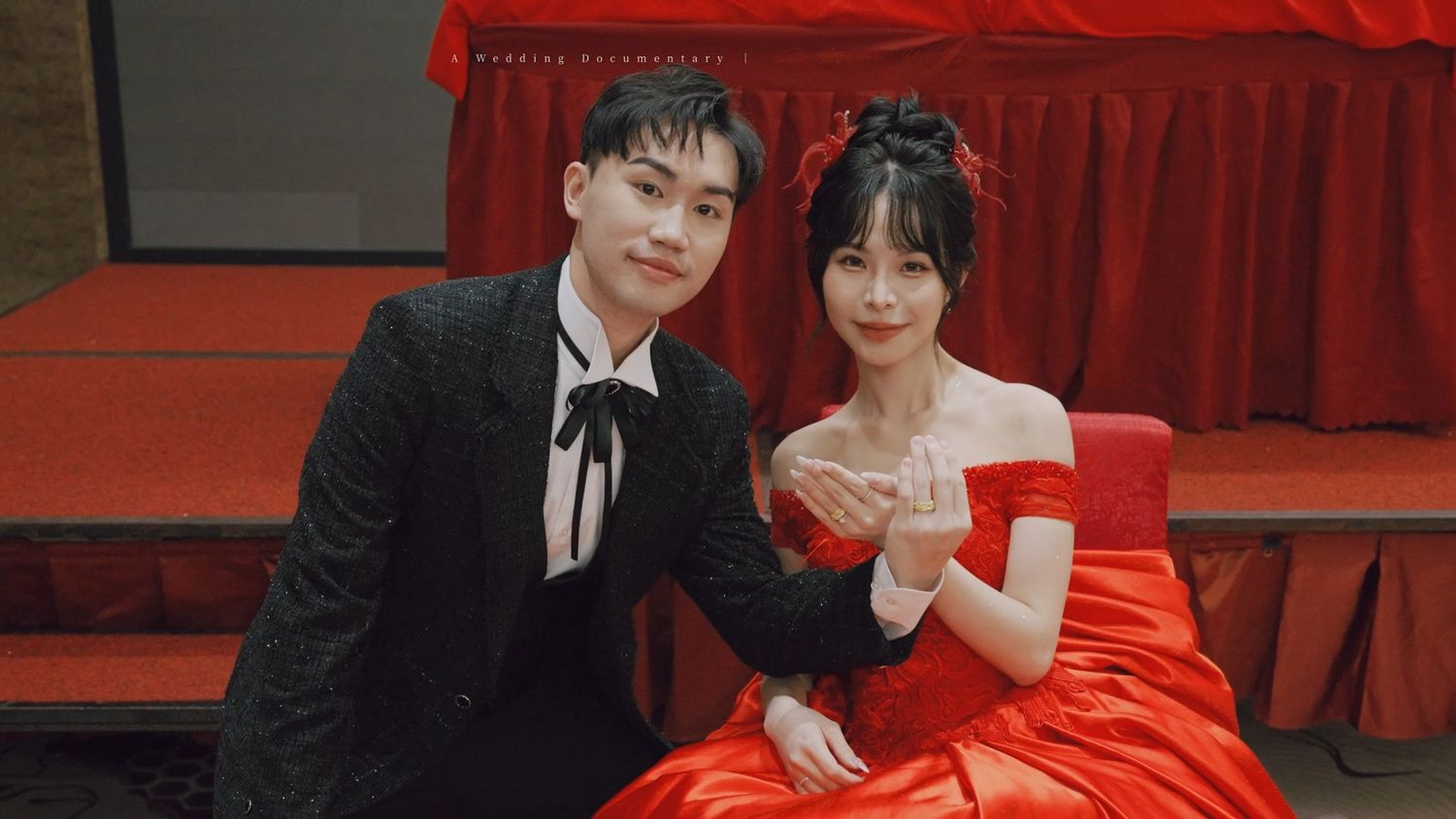 The couple seated on stage in red and black