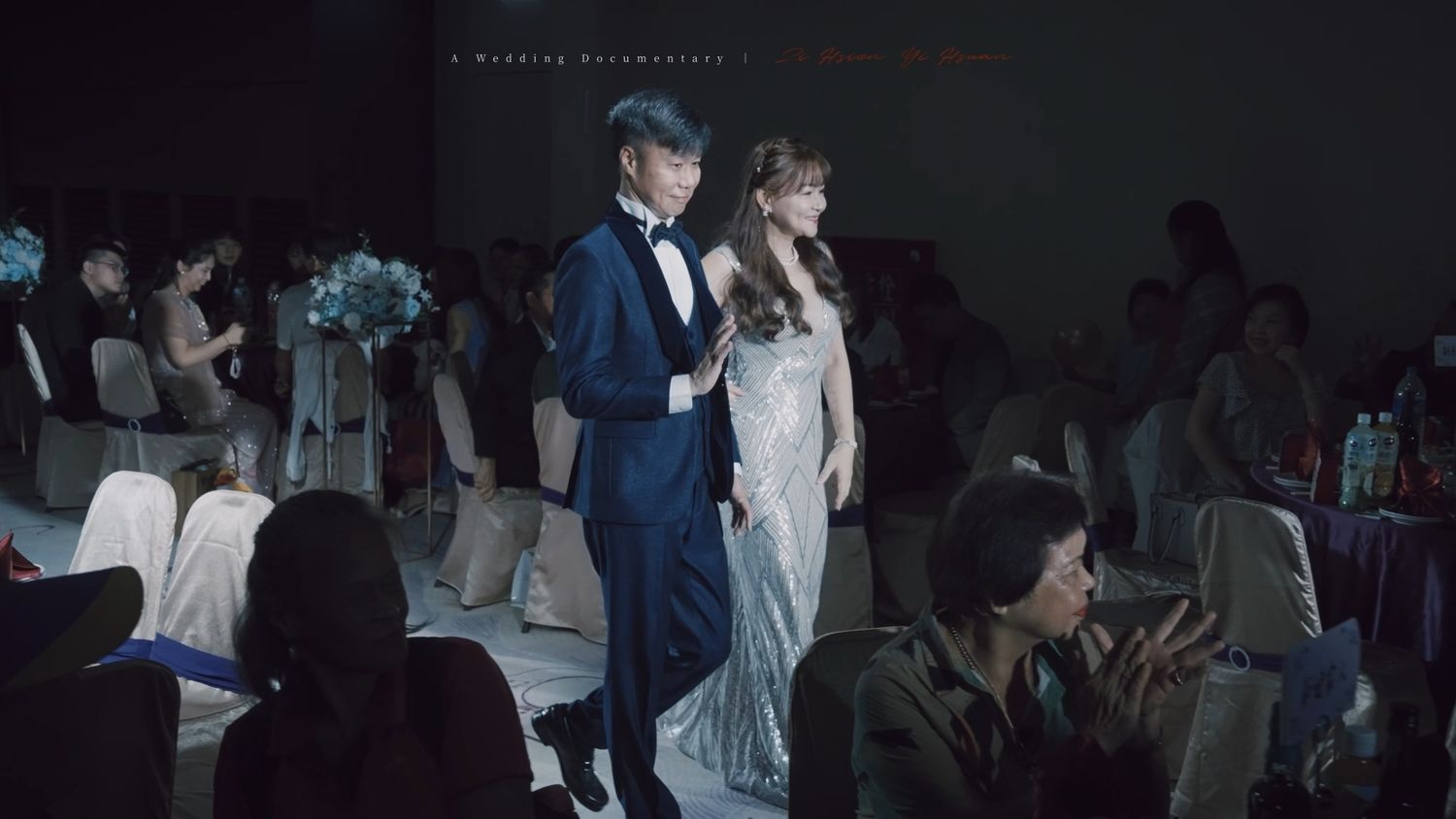 The couple walking through the dim banquet hall